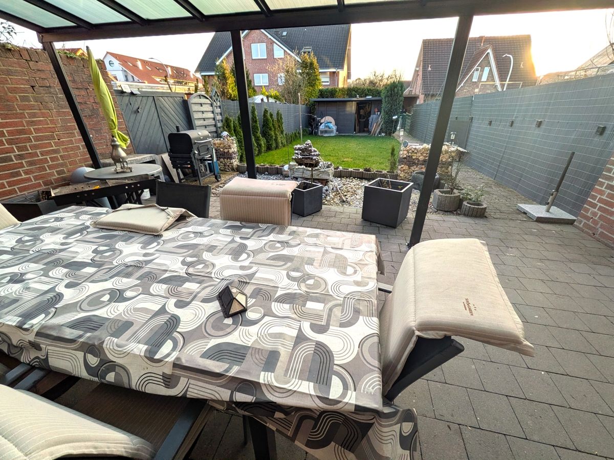Großzügige Terrasse mit Gartenbereich und der dahinter liegenden Garage